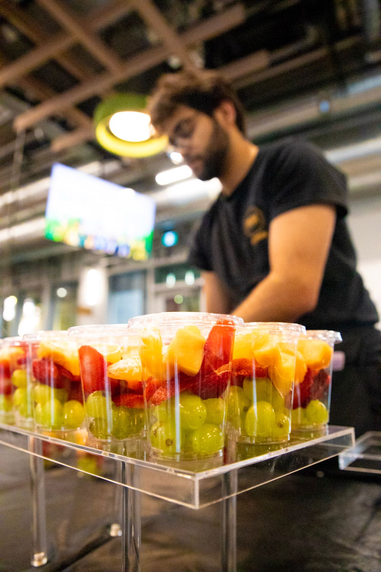 Cups of fresh-cut fruit lined up on a clear stand