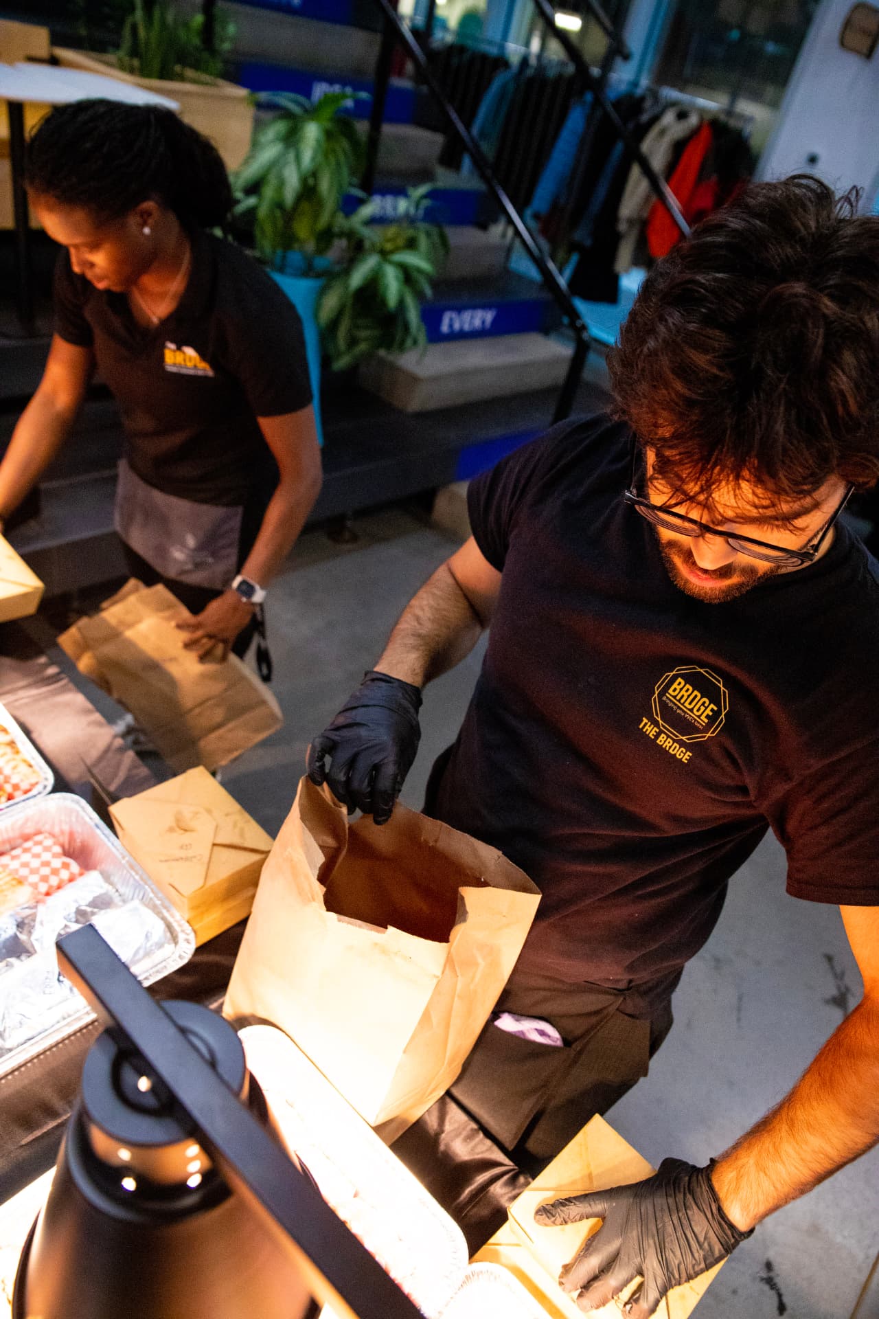 Two BRDGE team members packing paper bags and boxes for an event