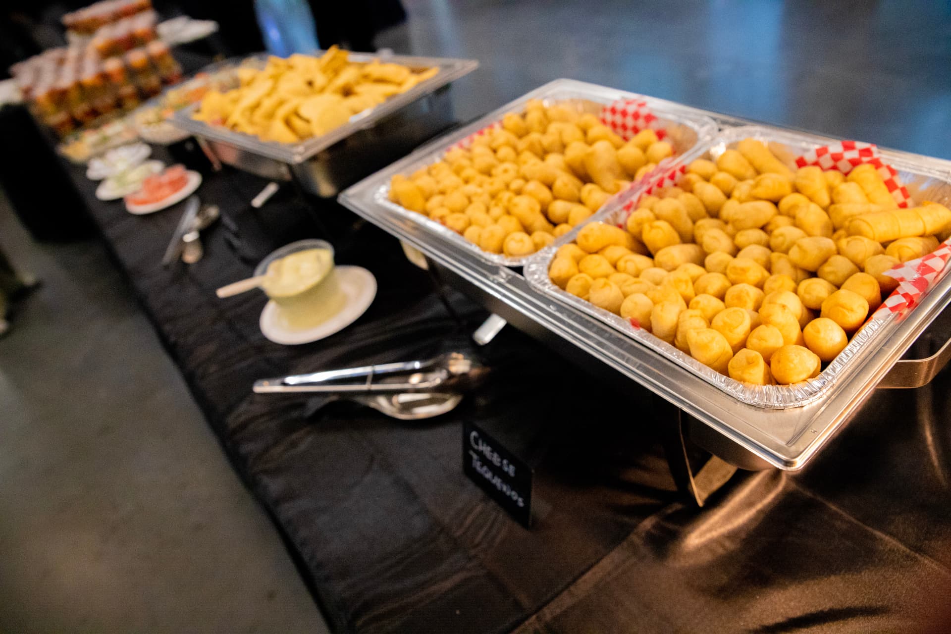 Cheese tequeños piled in a chafing dish, ready to serve